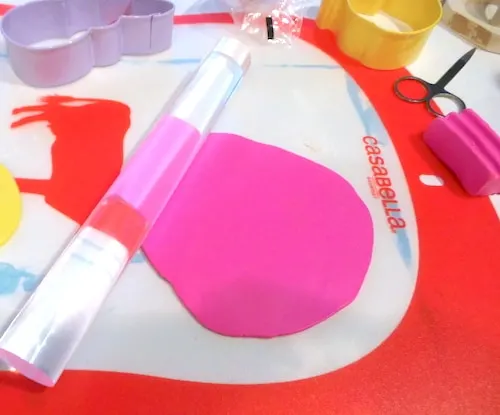 Rolling out hot pink clay with a clay roller