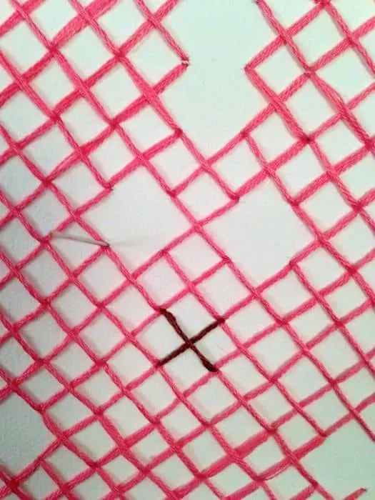 Pink embroidery thread on white canvas