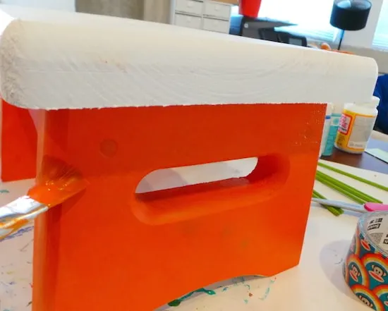 Painting the base of a wooden stool with orange paint