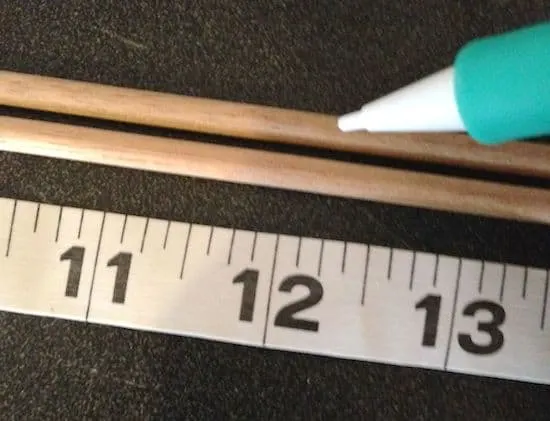 Marking lines with a pencil on dowel rods using a tape measure