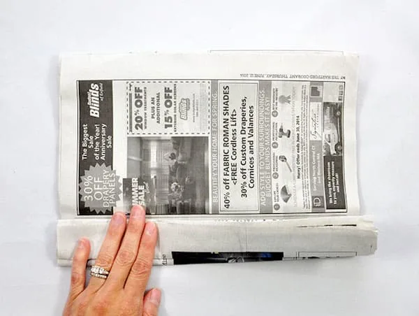 Folding the edge of the newspaper at the bottom