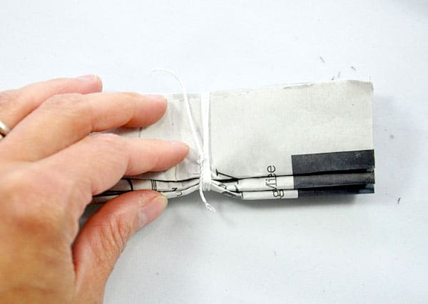 Tying string in the middle of the folded newspaper