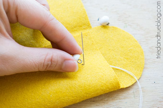 Hand sewing a button to the felt