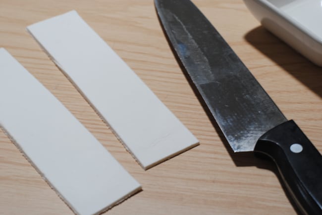 cutting two strips out of clay with a knife