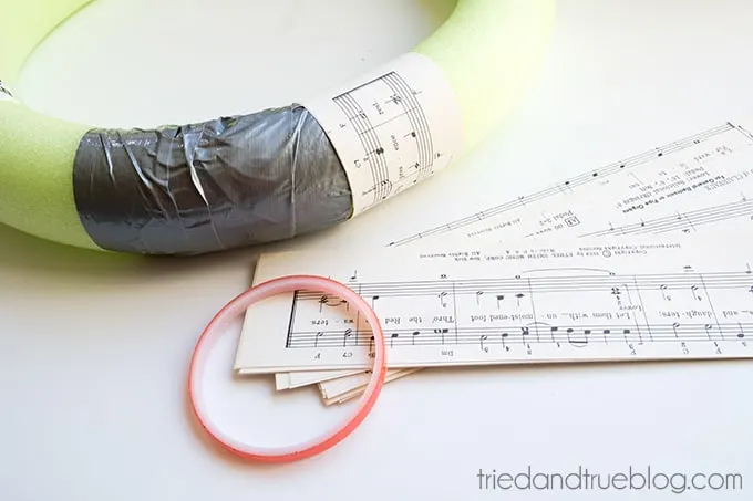 Pool noodle wreath form being covered with music sheets