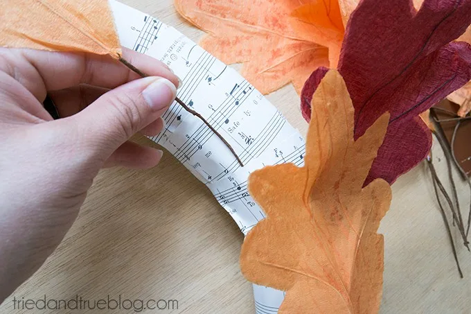 Inserting leaves into the paper on the wreath