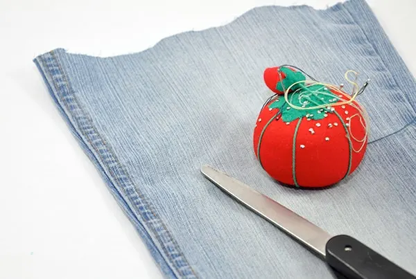 Part of a pant leg, tomato pin cushion, and a pair of scissors