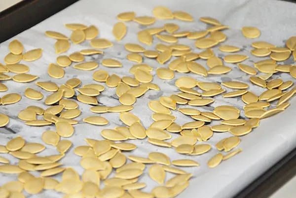 Pumpkin seeds being roasted on a cookie sheet