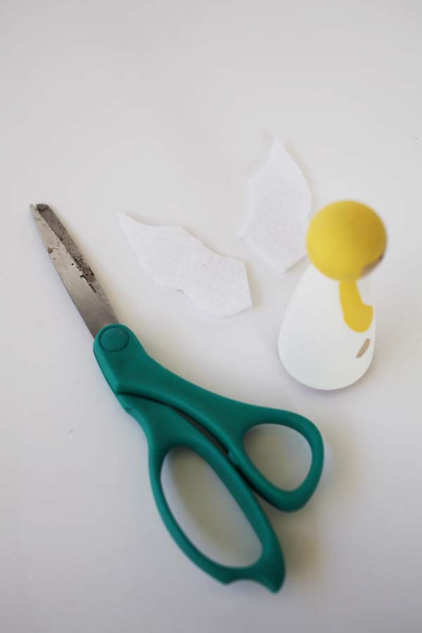 White felt cut into wings, an angel painted peg doll, and scissors