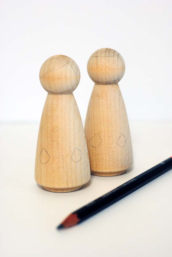 Drawing on wood peg dolls with a pencil