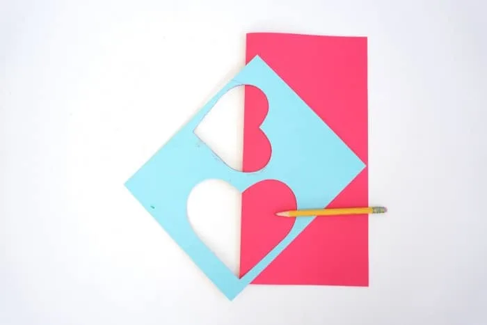 Tracing a heart template on pink paper with a pencil