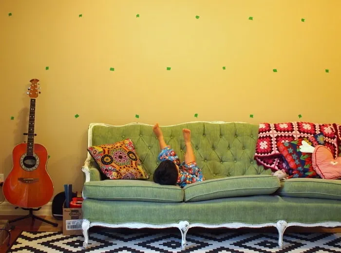 Masking tape marks on the wall with a green couch and guitar