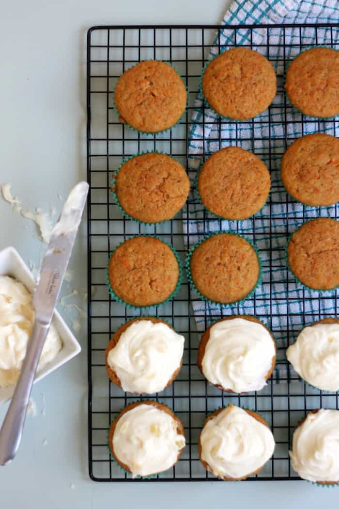 Spreading cream cheese icing on carrot cake muffins
