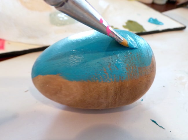 Painting a wood Easter egg with blue acrylic paint