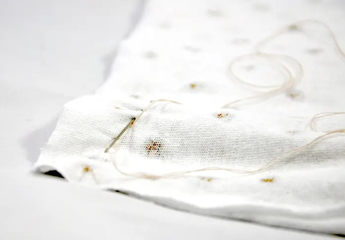 Hand stitching two pieces of t-shirt together with a needle