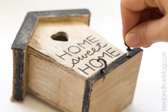 Screwing cup hooks into the base of the birdhouse