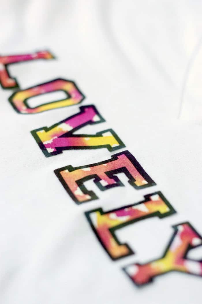 Iron on letters spelling LOVELY on the front of a white t shirt