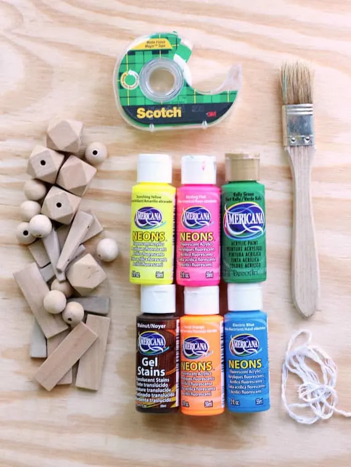 Wood beads, scotch tape, acrylic paint, a paintbrush, and twine