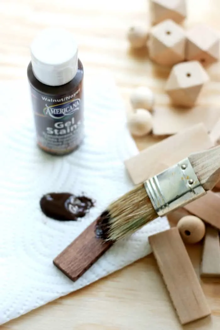 Painting gel stain onto a wood bead with a paintbrush