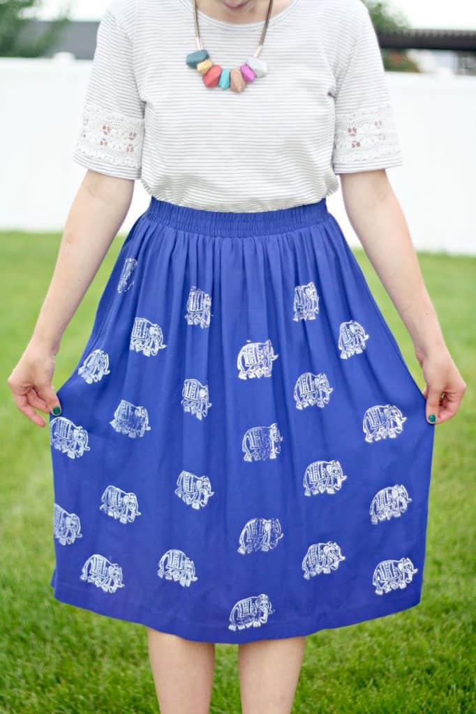 Woman wearing a white and gray striped shirt with a blue skirt with elephants stamped on it using fabric paint