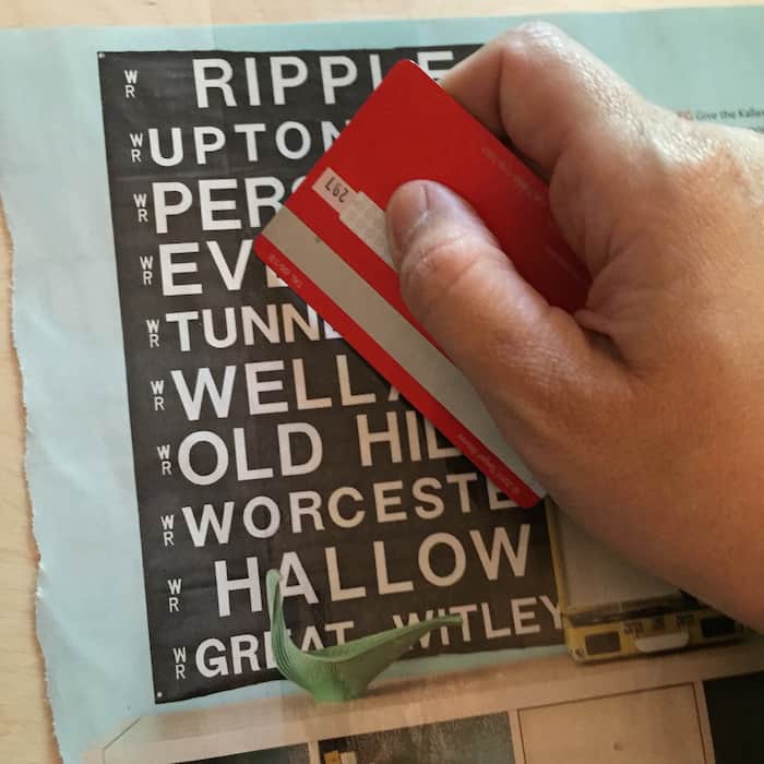 Smoothing packing tape onto a magazine page with a credit card