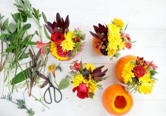 Bouquets of flowers being placed into carved out pumpkins