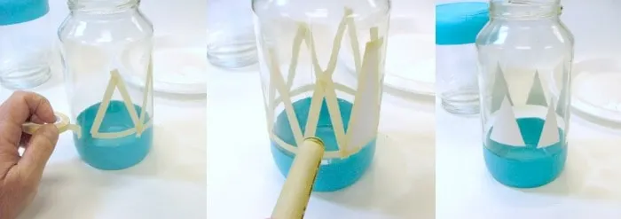 Taping off a glass jar to paint white Christmas tree shapes