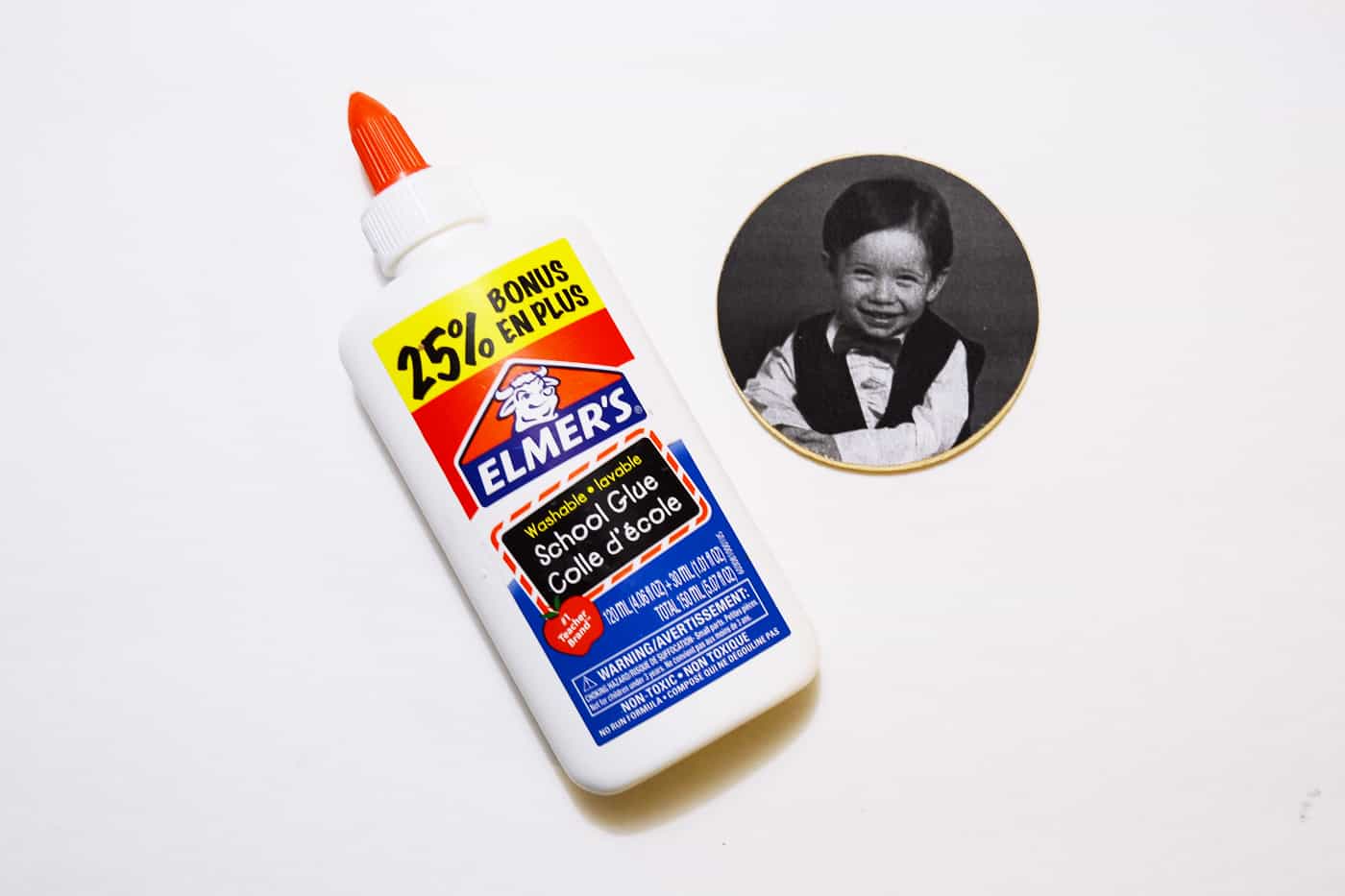 Bottle of glue and a black and white photo on a wood circle