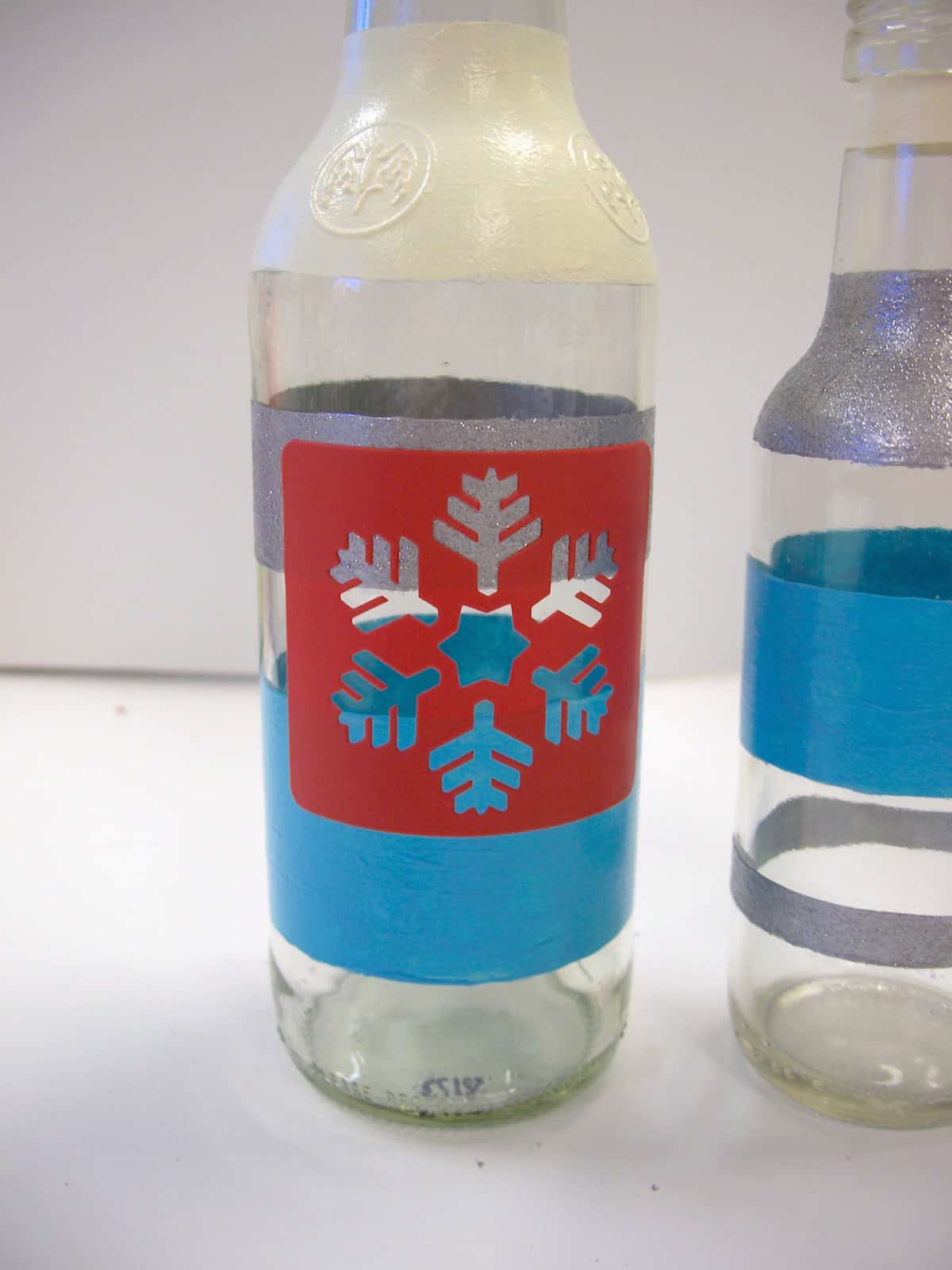 Painted bottle with a red adhesive snowflake stencil on top