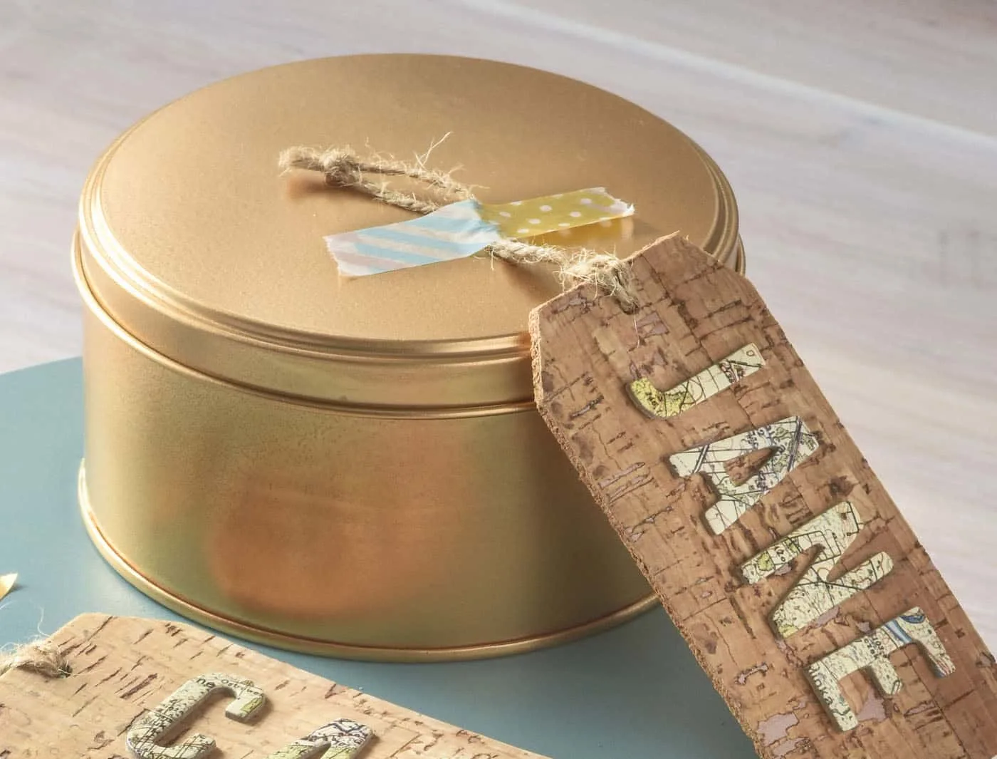 Gold spray painted cookie tin with a cork tag that says "Jane"
