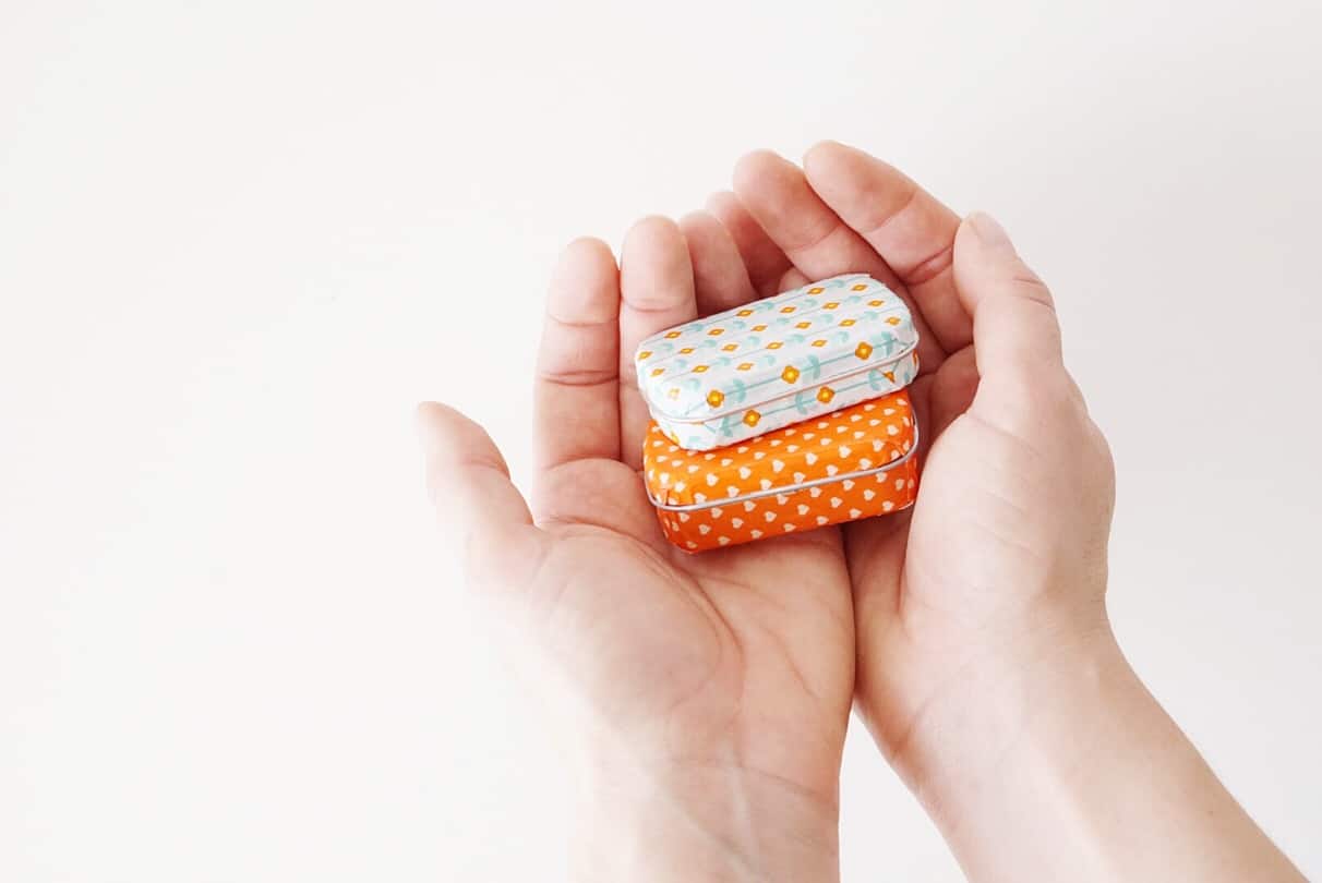 Altoid tins covered in washi tape sitting stacked in someone's hands