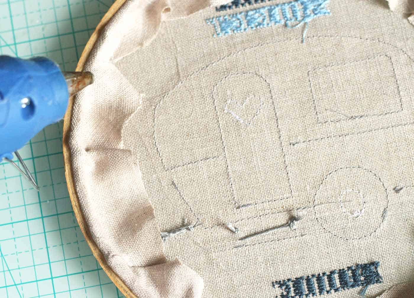 Finishing and folding the back on the embroidery with a hot glue gun