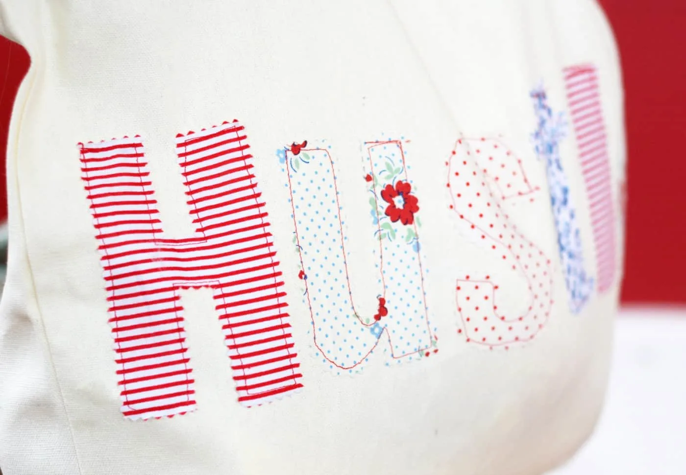 Letters sewn onto the front of a tote spelling the word Hustle