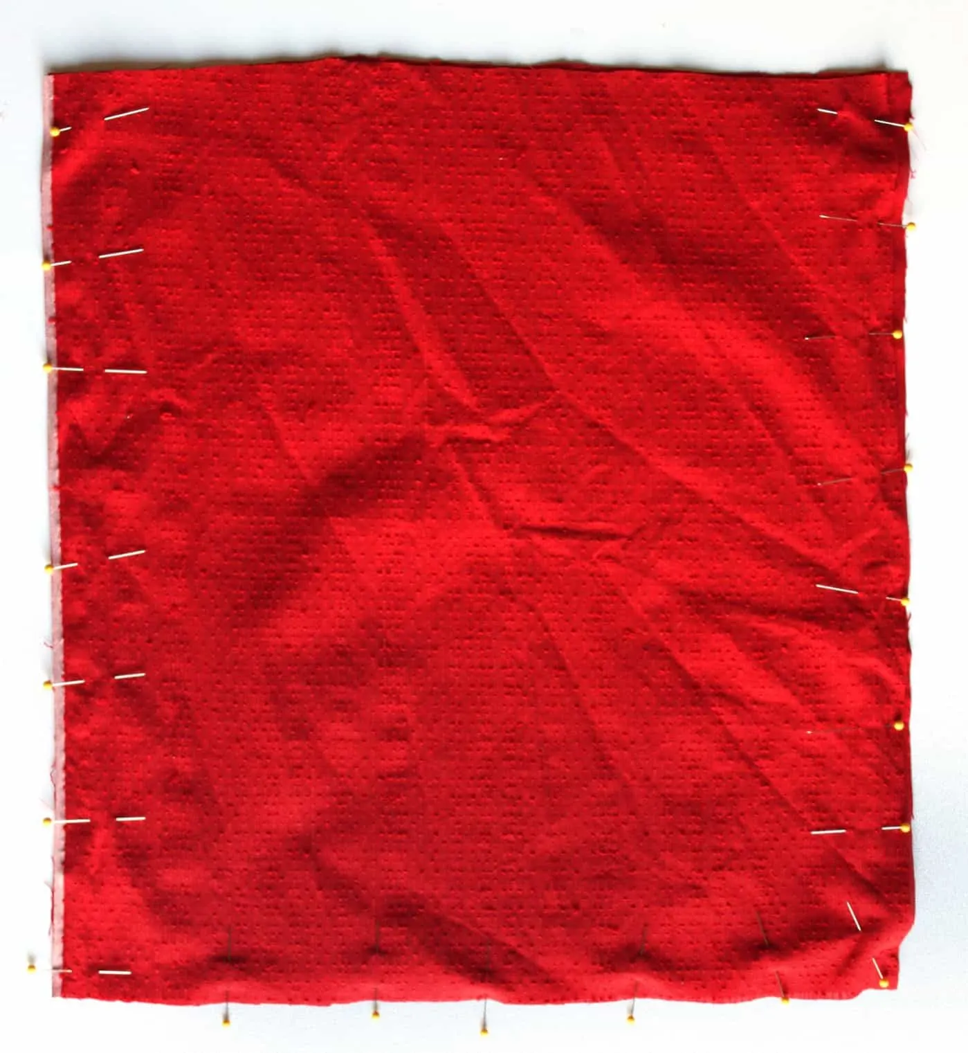 Red fabric lining pinned together on a work surface