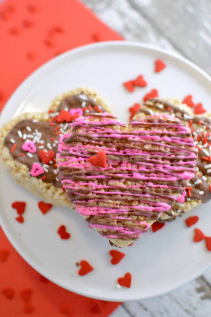 This Rice Krispie treat recipe is made extra awesome for Valentine's Day with the heart shape and the addition of chocolate drizzle and sprinkles. So fun!