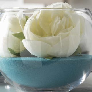 Cheap diy wedding centerpieces using craft sand, faux flowers, and glass bubble bowls