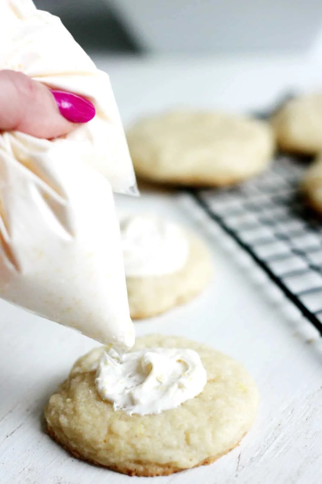 Spreading cream cheese icing on the top of a lemon cookie