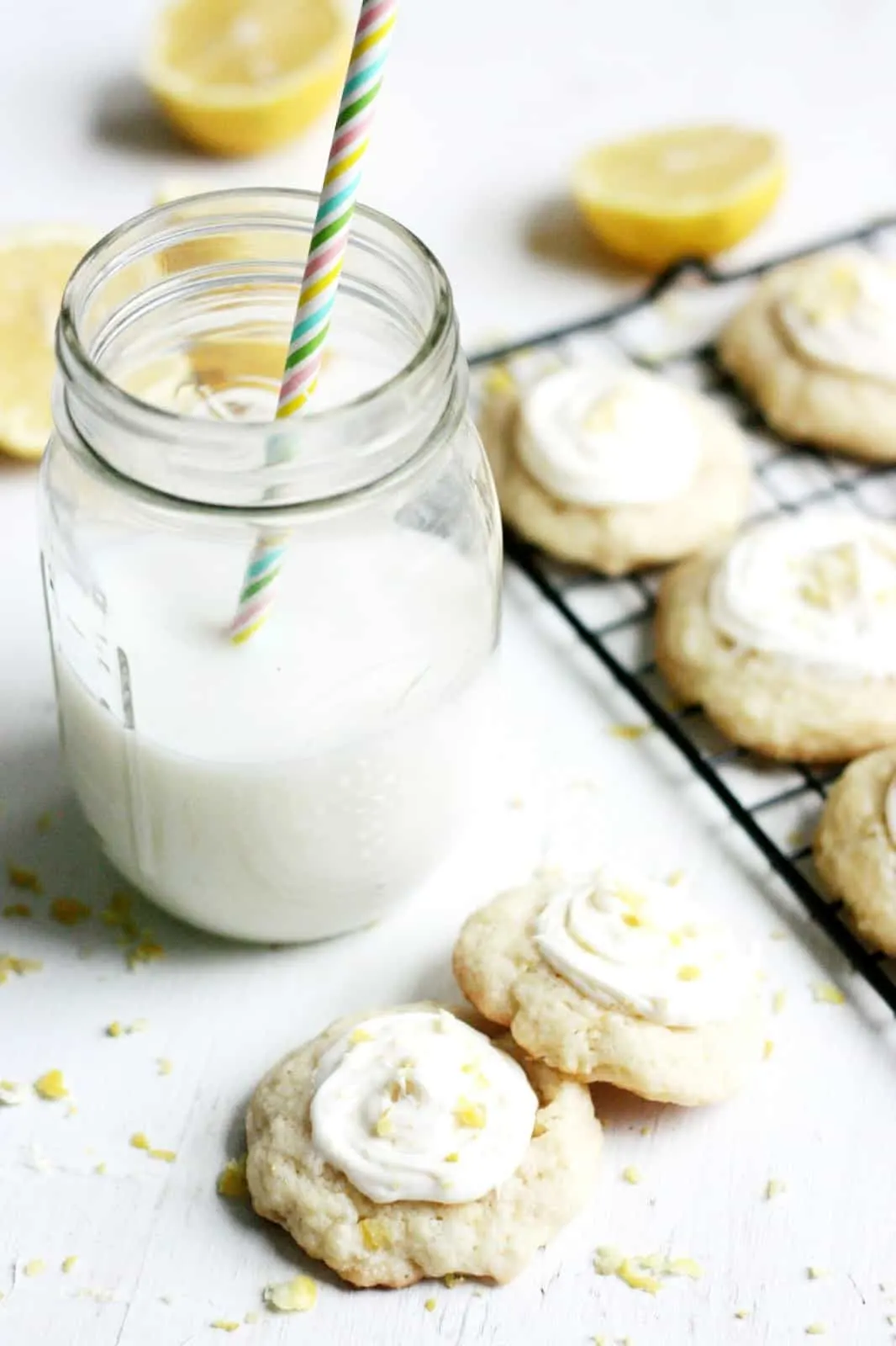 lemon cookies with icing and a mason jar glass of milk with a colorful straw