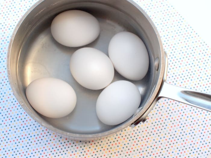 White eggs hard boiling in a pan
