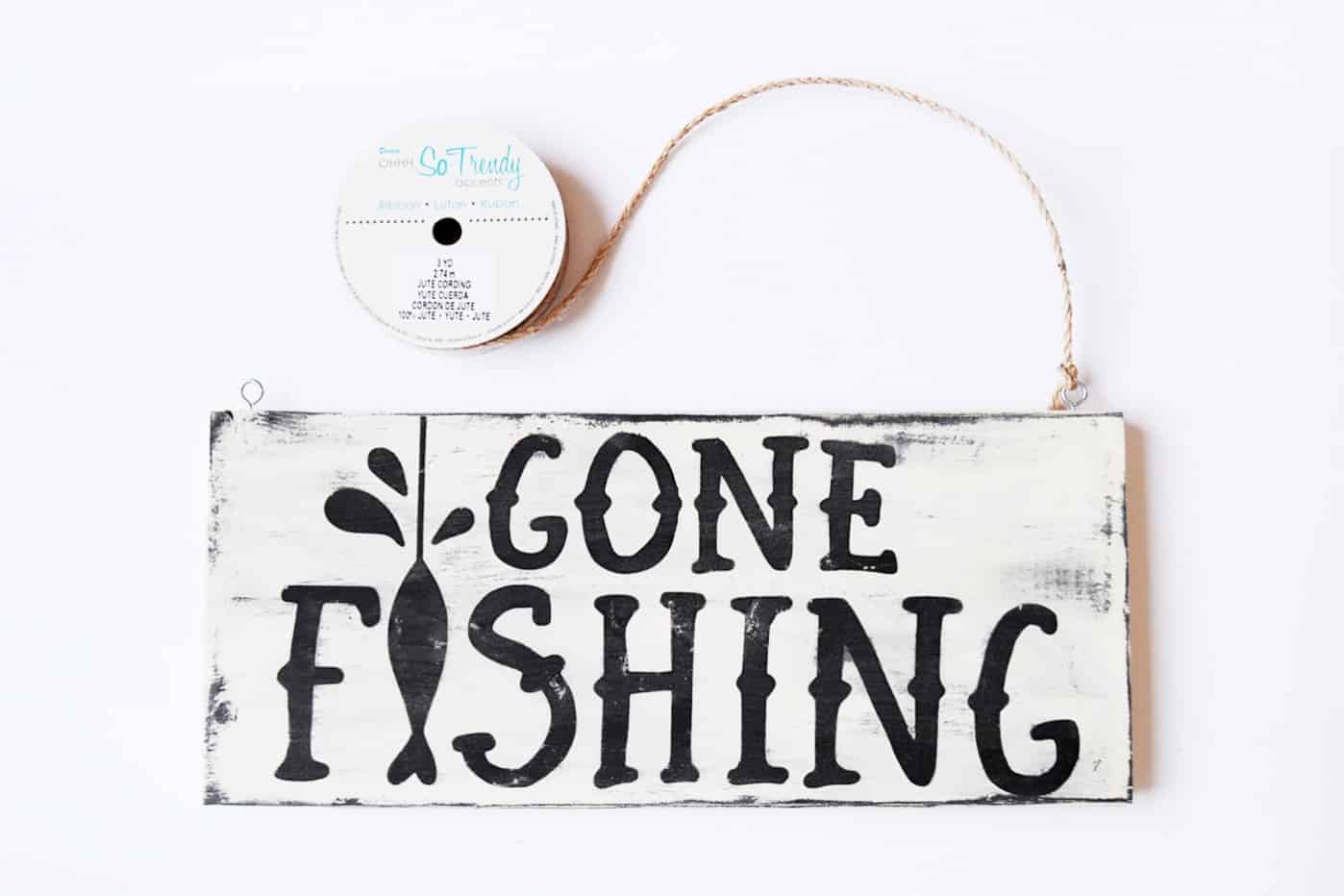 Tying jute to a gone fishing sign