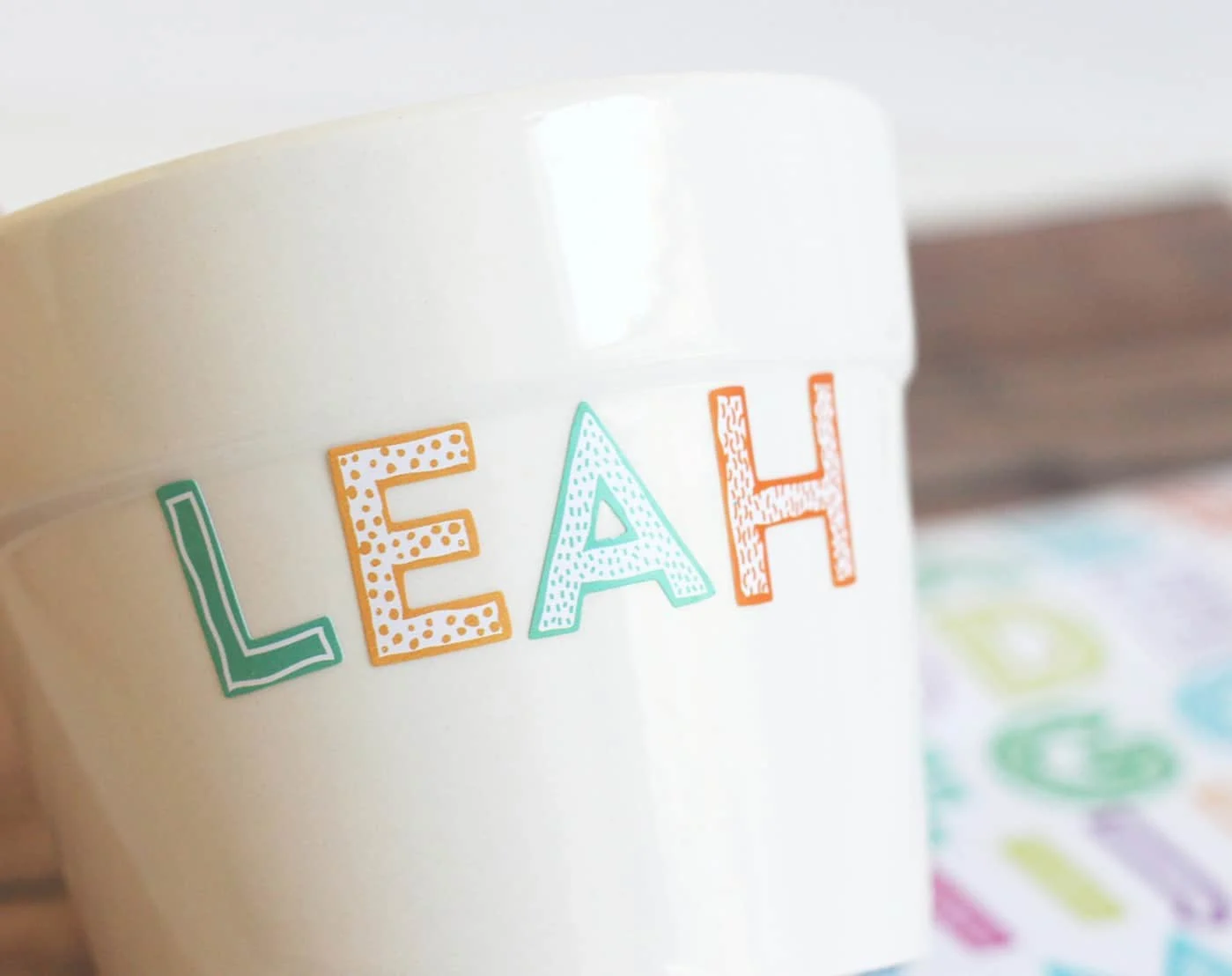 Stickers spelling "LEAH" applied to the side of a white ceramic pot