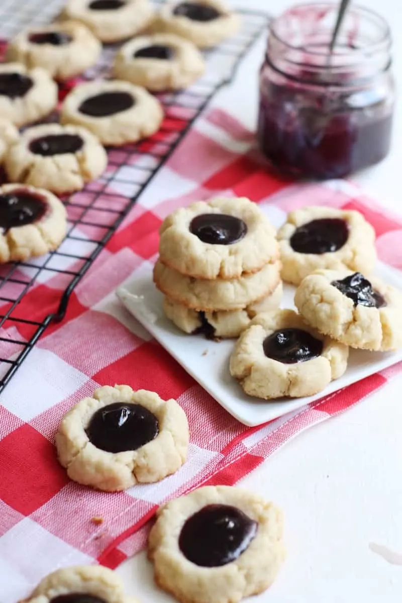 Lemon blueberry jam thumbprint cookies stacked on a plate
