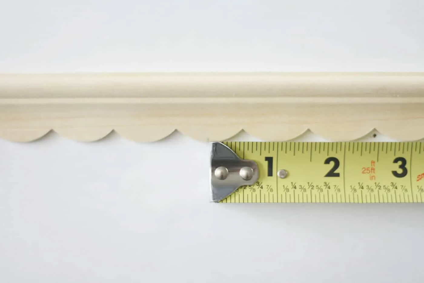 Measuring tape next to a piece of wood trim