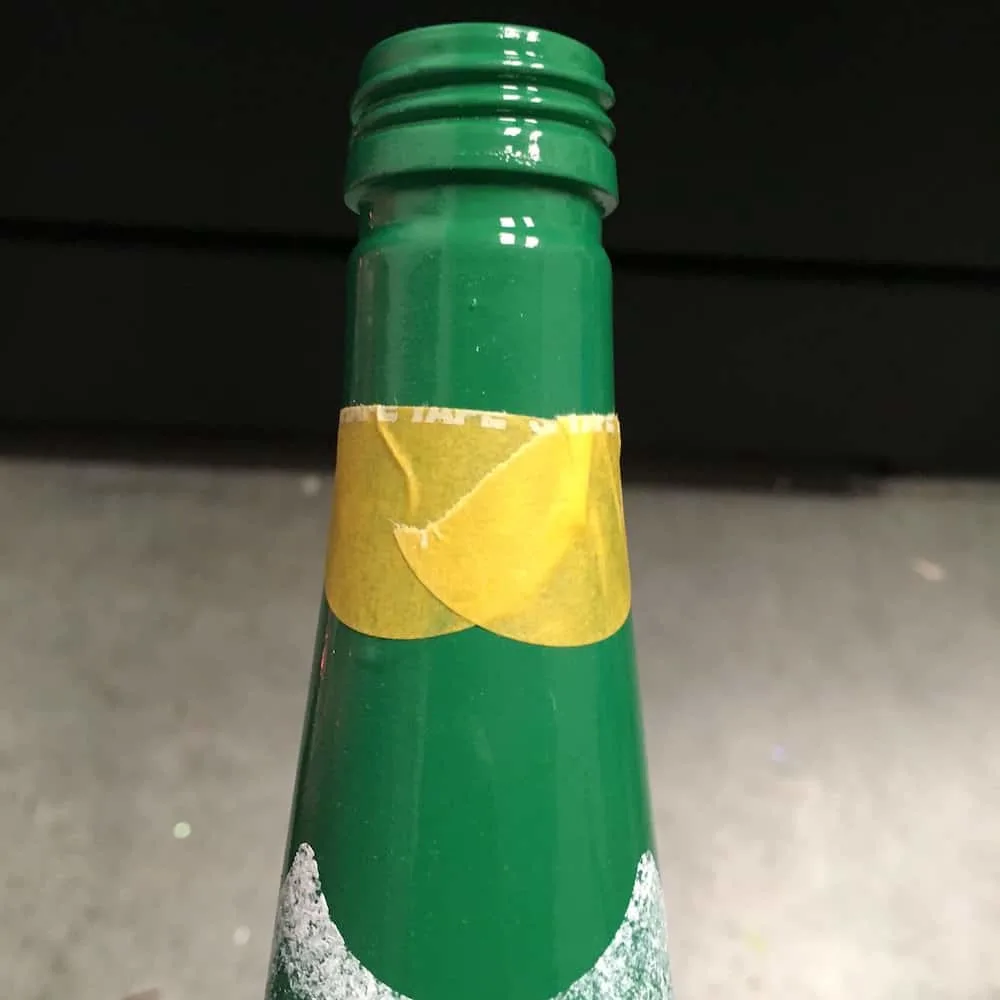 Top of the bottle with stencil tape wrapped around
