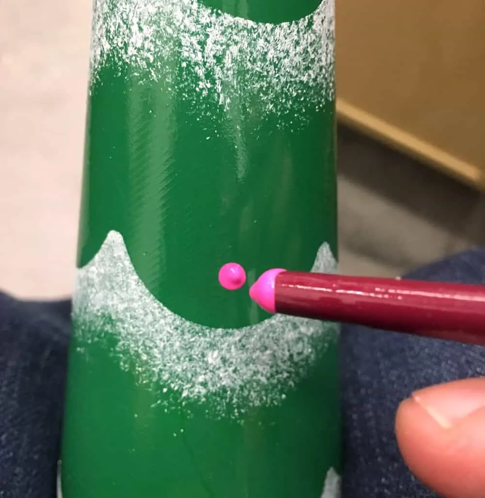 Dotting painted ornaments on the bottle with the end of a paintbrush