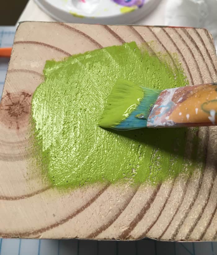 Painting a wood block with green acrylic paint