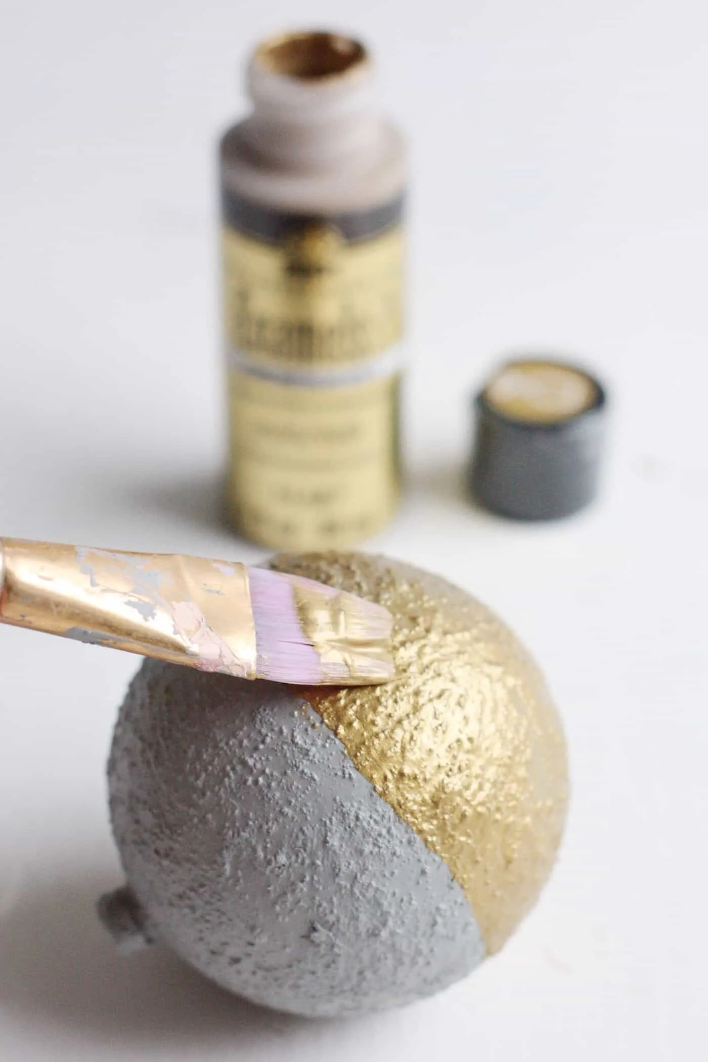 Painting the bottom half of a cement ornament with metallic gold paint