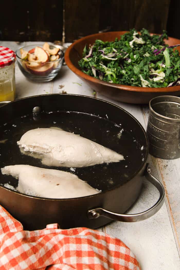 Boiled chicken breasts sitting in water in a pan