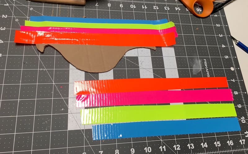 Cover the cardboard pieces with orange, pink, neon yellow, and blue Duck Tape