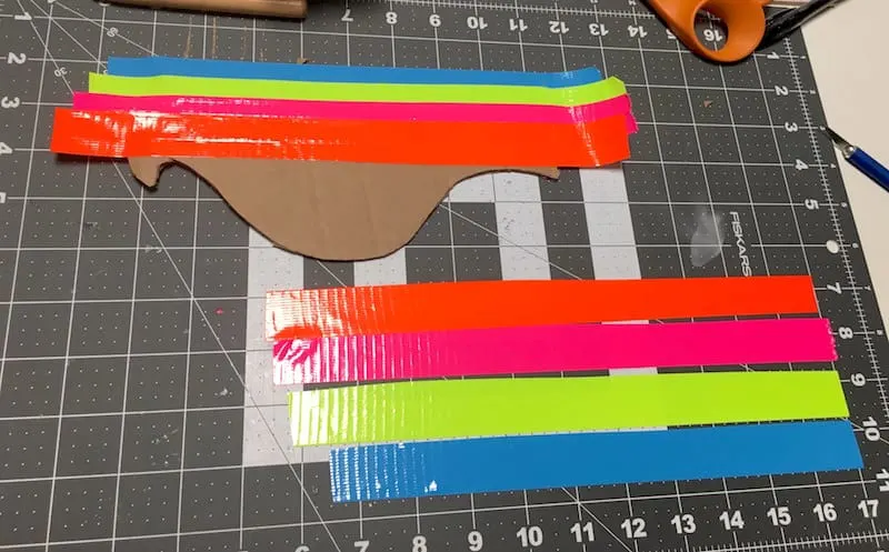 Cover the cardboard pieces with orange, pink, neon yellow, and blue Duck Tape